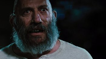 Movie still from “The Devil's Rejects” (2005), directed by Rob Zombie – An old man with a beard and a white t - shirt; Close Up shot, Low angle