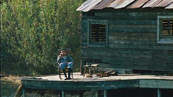 Movie still from “The Devil's Rejects” (2005), directed by Rob Zombie – An old man sitting in a chair on a porch; Extreme Wide shot, High angle