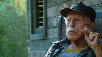 Movie still from “The Devil's Rejects” (2005), directed by Rob Zombie – An older man wearing a hat and a yellow shirt; Close Up shot, Low angle
