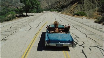 Movie still from “The Devil's Rejects” (2005), directed by Rob Zombie – Two people in the back seat of a blue convertible car; Wide shot, High angle
