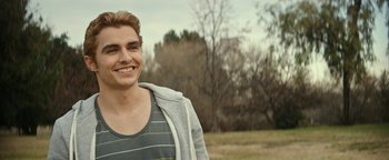 Movie still from “The Disaster Artist” (2017), directed by James Franco – A young man smiling for the camera in a field; Close Up shot, Over the shoulder angle