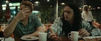 Movie still from “The Disaster Artist” (2017), directed by James Franco – Two people sitting at a table with a plate of food; Medium shot, Over the shoulder angle