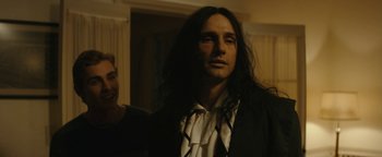Movie still from “The Disaster Artist” (2017), directed by James Franco – A man with long black hair wearing a white shirt; Medium shot, Over the shoulder angle