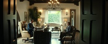 Movie still from “The Disaster Artist” (2017), directed by James Franco – Two people are sitting in chairs in a living room; Wide shot, Low angle