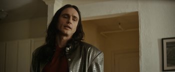 Movie still from “The Disaster Artist” (2017), directed by James Franco – A man with long black hair standing in front of a wall; Close Up shot, Low angle