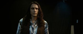Movie still from “The Disaster Artist” (2017), directed by James Franco – A man with long black hair wearing a leopard print vest; Close Up shot, Low angle