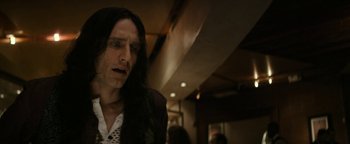 Movie still from “The Disaster Artist” (2017), directed by James Franco – A man with long black hair is standing in front of a wall; Close Up shot, Low angle