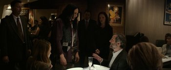Movie still from “The Disaster Artist” (2017), directed by James Franco – A group of people standing around a table; Medium shot, Over the shoulder angle
