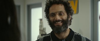 Movie still from “The Disaster Artist” (2017), directed by James Franco – A man with a goatee and glasses smiling for the camera; Close Up shot, Over the shoulder angle