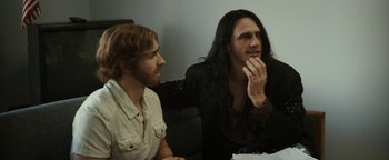 Movie still from “The Disaster Artist” (2017), directed by James Franco – Two men sitting next to each other on a couch; Medium shot, Over the shoulder angle
