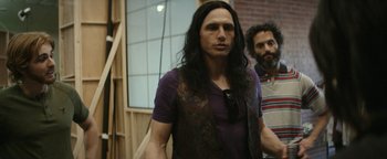 Movie still from “The Disaster Artist” (2017), directed by James Franco – A man with long black hair standing next to another man; Medium shot, Over the shoulder angle