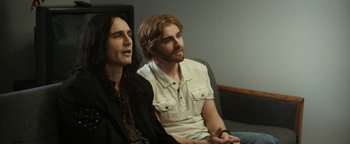 Movie still from “The Disaster Artist” (2017), directed by James Franco – A couple of men sitting next to each other on top of a couch; Medium shot, Over the shoulder angle