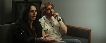 Movie still from “The Disaster Artist” (2017), directed by James Franco – A man and a woman are sitting on a couch; Medium shot, Over the shoulder angle