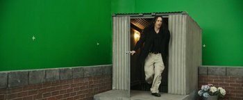 Movie still from “The Disaster Artist” (2017), directed by James Franco – A man with long black hair is walking out of a building; Wide shot, Over the shoulder angle