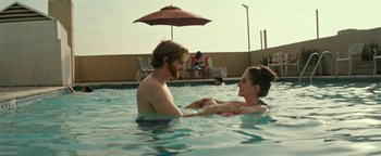 Movie still from “The Disaster Artist” (2017), directed by James Franco – A man and a woman in a swimming pool with an umbrella; Medium shot, Over the shoulder angle