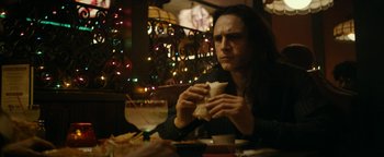 Movie still from “The Disaster Artist” (2017), directed by James Franco – A man sitting at a table eating a sandwich; Medium shot, Over the shoulder angle