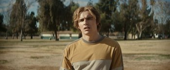 Movie still from “The Disaster Artist” (2017), directed by James Franco – A young man with blonde hair wearing a yellow and gray shirt; Close Up shot, Over the shoulder angle