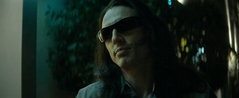 Movie still from “The Disaster Artist” (2017), directed by James Franco – A man with long black hair wearing sunglasses; Close Up shot, Low angle
