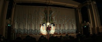 Movie still from “The Disaster Artist” (2017), directed by James Franco – A man standing on a stage in front of a curtain; Extreme Wide shot, Low angle