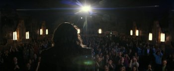 Movie still from “The Disaster Artist” (2017), directed by James Franco – A crowd of people in a room with a microphone; Wide shot, Over the shoulder angle