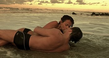 Movie still from “The Diving Bell and the Butterfly” (2007), directed by Julian Schnabel – A man and a woman kissing on the beach; Medium shot, High angle