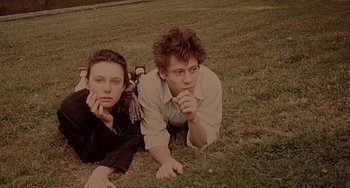 Movie still from “The Diving Bell and the Butterfly” (2007), directed by Julian Schnabel – Two young men laying in the grass with their hands under their chin; Close Up shot, Overhead angle