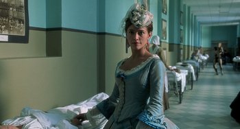 Movie still from “The Diving Bell and the Butterfly” (2007), directed by Julian Schnabel – A woman dressed in period clothing poses for a picture; Medium shot, Low angle