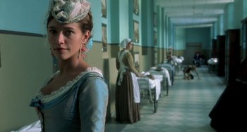 Movie still from “The Diving Bell and the Butterfly” (2007), directed by Julian Schnabel – A woman standing in front of a row of tables; Medium shot, Low angle