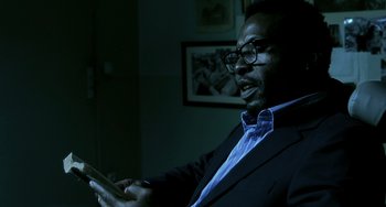 Movie still from “The Diving Bell and the Butterfly” (2007), directed by Julian Schnabel – A man in a suit and glasses is holding a tablet; Medium shot, Low angle