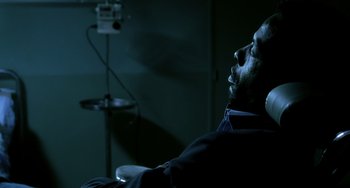 Movie still from “The Diving Bell and the Butterfly” (2007), directed by Julian Schnabel – A man sitting in a chair in a dark room; Close Up shot, High angle