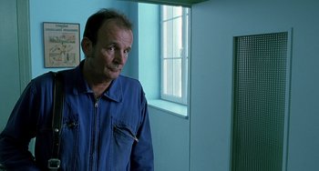 Movie still from “The Diving Bell and the Butterfly” (2007), directed by Julian Schnabel – A man standing in front of a window in a room; Close Up shot, Over the shoulder angle