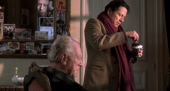 Movie still from “The Diving Bell and the Butterfly” (2007), directed by Julian Schnabel – A man in a brown coat and a man in a red scarf; Medium shot, Over the shoulder angle