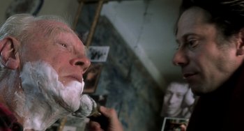 Movie still from “The Diving Bell and the Butterfly” (2007), directed by Julian Schnabel – A man shaving another man's face in front of a mirror; Close Up shot, Over the shoulder angle