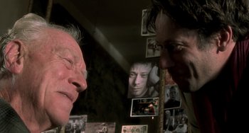 Movie still from “The Diving Bell and the Butterfly” (2007), directed by Julian Schnabel – Two men talking in front of a bunch of pictures; Close Up shot, Over the shoulder angle