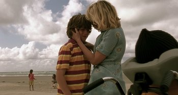 Movie still from “The Diving Bell and the Butterfly” (2007), directed by Julian Schnabel – A young boy and a woman standing on the beach; Medium shot, Over the shoulder angle