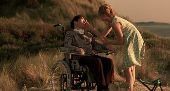 Movie still from “The Diving Bell and the Butterfly” (2007), directed by Julian Schnabel – A man sitting in a wheel chair next to a woman; Medium shot, Low angle