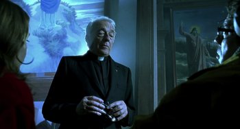 Movie still from “The Diving Bell and the Butterfly” (2007), directed by Julian Schnabel – An older man wearing a priest's outfit; Medium shot, Low angle