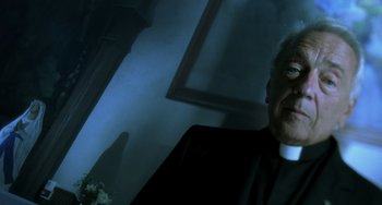 Movie still from “The Diving Bell and the Butterfly” (2007), directed by Julian Schnabel – A man wearing a priest's outfit is sitting in front of a mirror; Close Up shot, Low angle