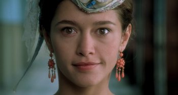 Movie still from “The Diving Bell and the Butterfly” (2007), directed by Julian Schnabel – A person wearing a hat and earrings; Close Up shot, Over the shoulder angle