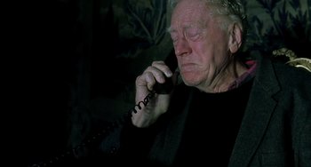 Movie still from “The Diving Bell and the Butterfly” (2007), directed by Julian Schnabel – An old man talking on a phone while sitting on a couch; Close Up shot, High angle