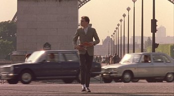Movie still from “The Dreamers” (2003), directed by Bernardo Bertolucci – A man is walking down the street holding a book in his hand; Wide shot, Low angle
