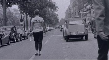 Movie still from “The Dreamers” (2003), directed by Bernardo Bertolucci – A woman walking down the street with a bag in her hand; Wide shot, Low angle