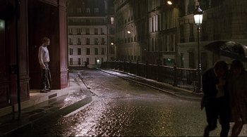 Movie still from “The Dreamers” (2003), directed by Bernardo Bertolucci – A wet street at night with buildings on both sides of the street; Extreme Wide shot, High angle