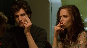 Movie still from “The Dreamers” (2003), directed by Bernardo Bertolucci – A man and a woman sitting next to each other on their cell phones; Close Up shot, Over the shoulder angle