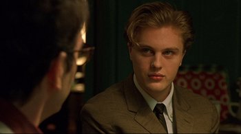 Movie still from “The Dreamers” (2003), directed by Bernardo Bertolucci – A man in a suit and tie looking at a man in glasses; Close Up shot, Over the shoulder angle