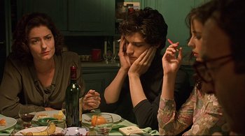 Movie still from “The Dreamers” (2003), directed by Bernardo Bertolucci – A group of people sitting at a table with food; Medium shot, Over the shoulder angle