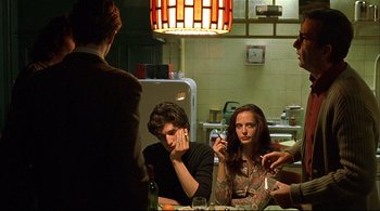 Movie still from “The Dreamers” (2003), directed by Bernardo Bertolucci – A group of people sitting around a table; Medium shot, Over the shoulder angle