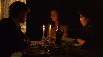 Movie still from “The Dreamers” (2003), directed by Bernardo Bertolucci – A group of people sitting around a table with candles; Medium shot, Over the shoulder angle