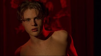 Movie still from “The Dreamers” (2003), directed by Bernardo Bertolucci – A young man posing for the camera in a dark room; Close Up shot, Over the shoulder angle