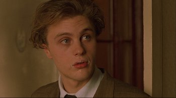 Movie still from “The Dreamers” (2003), directed by Bernardo Bertolucci – A young man in a suit and tie looking to his left; Close Up shot, Low angle